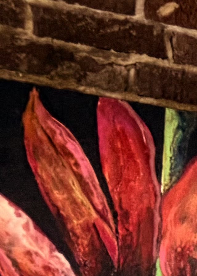 Painting of pink and red flowers against weathered exposed brick