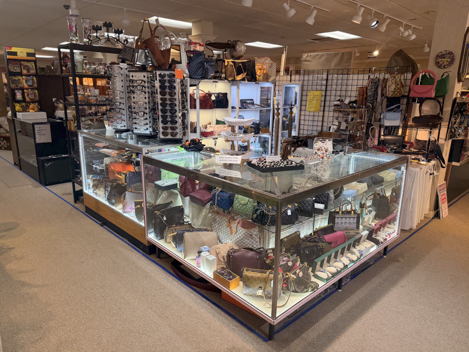Glass display cases of handbags surrounded by accessory racks